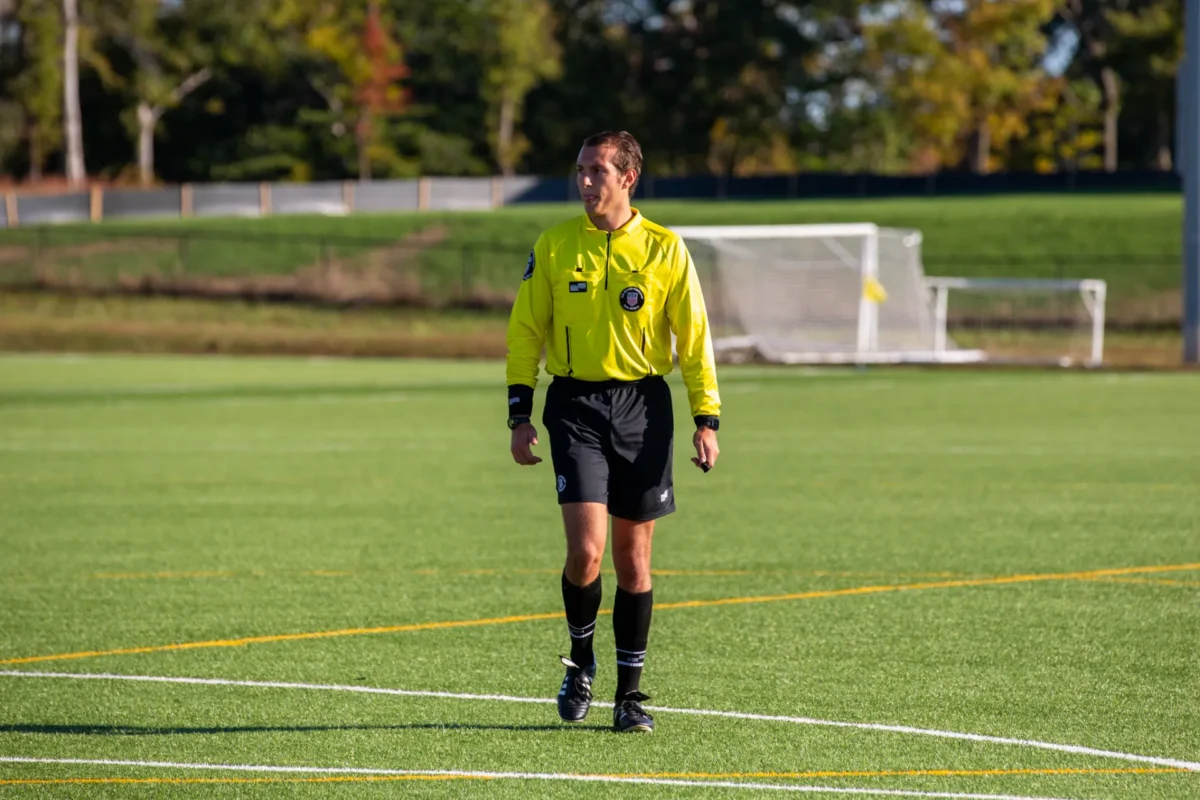 Center referee in a yellow kit walking across the field