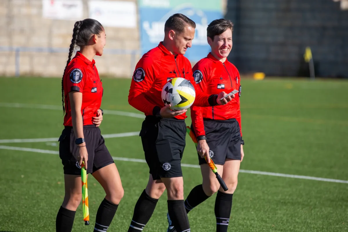 Three referees walking onto the field before a match